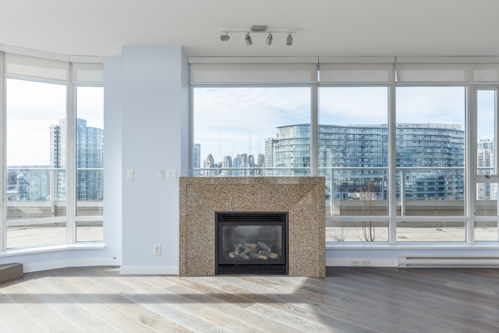fireplace with floor to ceiling windows to the outside behind it in living room of penthouse condo managed by birds nest properties
