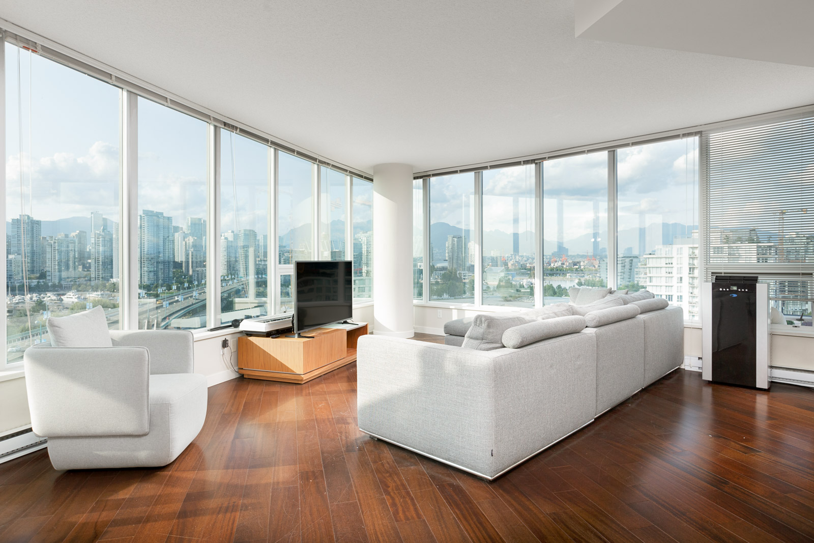 Living room white couches overlooks city skyline from Vancouver rental condo.