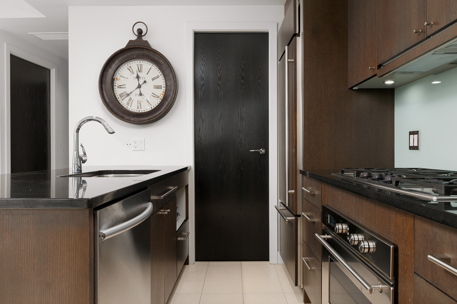 Condo kitchen with clock dishwasher stove and dark door