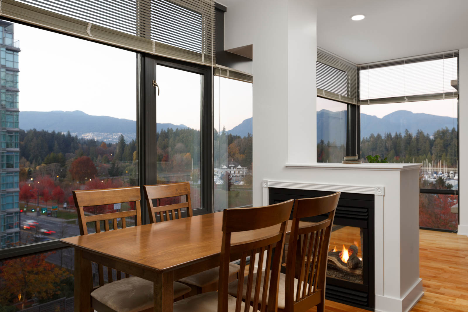 dining room with wood table and chairs in lumiere rental condo with view to outside of coal harbour and stanley park