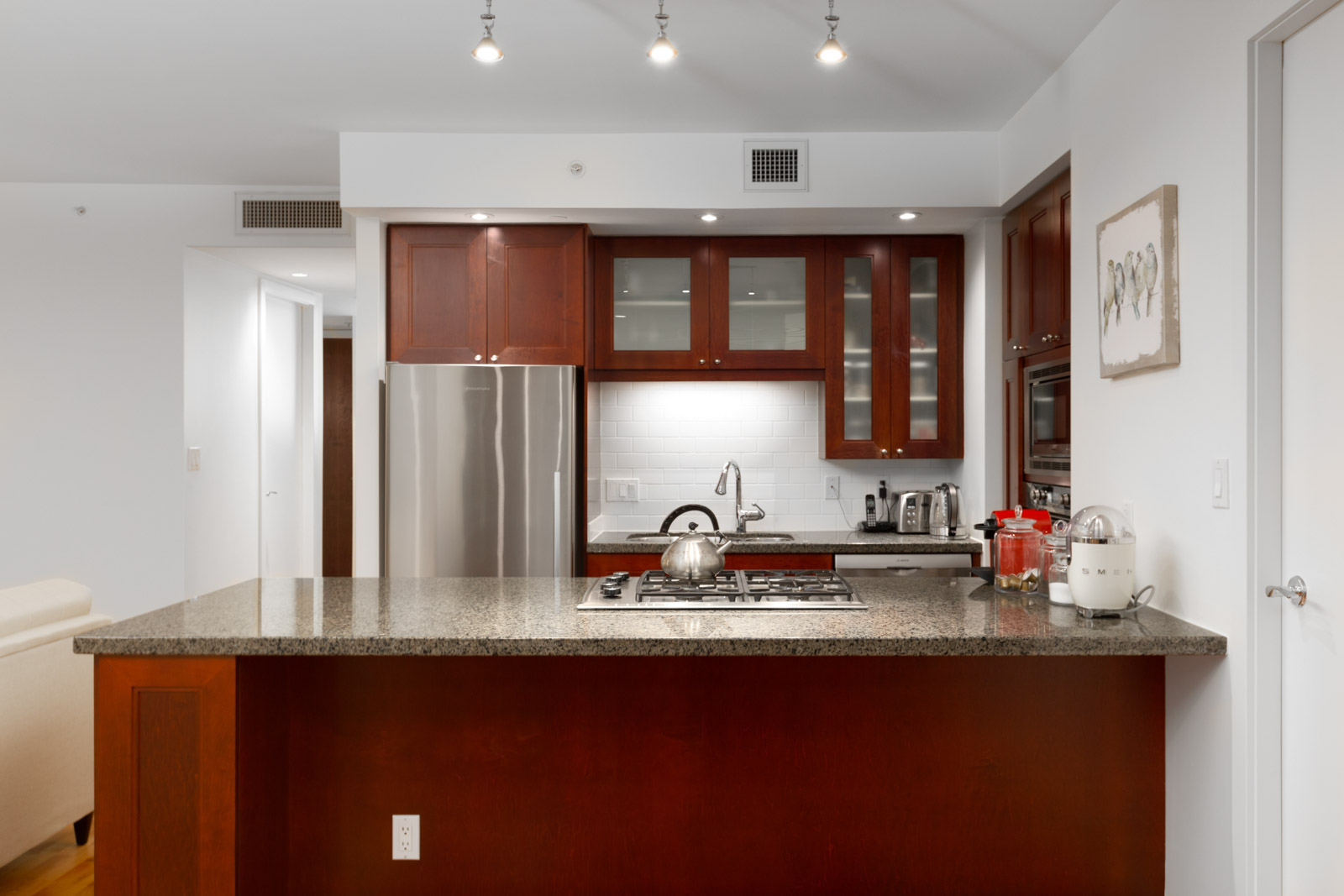 condo kitchen with wood cabinets and granite countertops in lumiere rental condo in west end vancouver