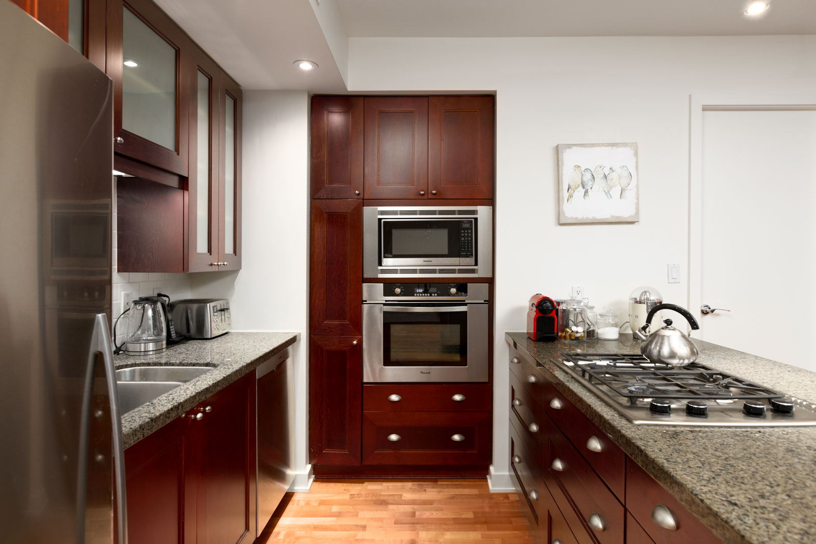 microwave and oven along wall of wood cabinets in kitchen of rental condo in lumiere building in west end vancouver