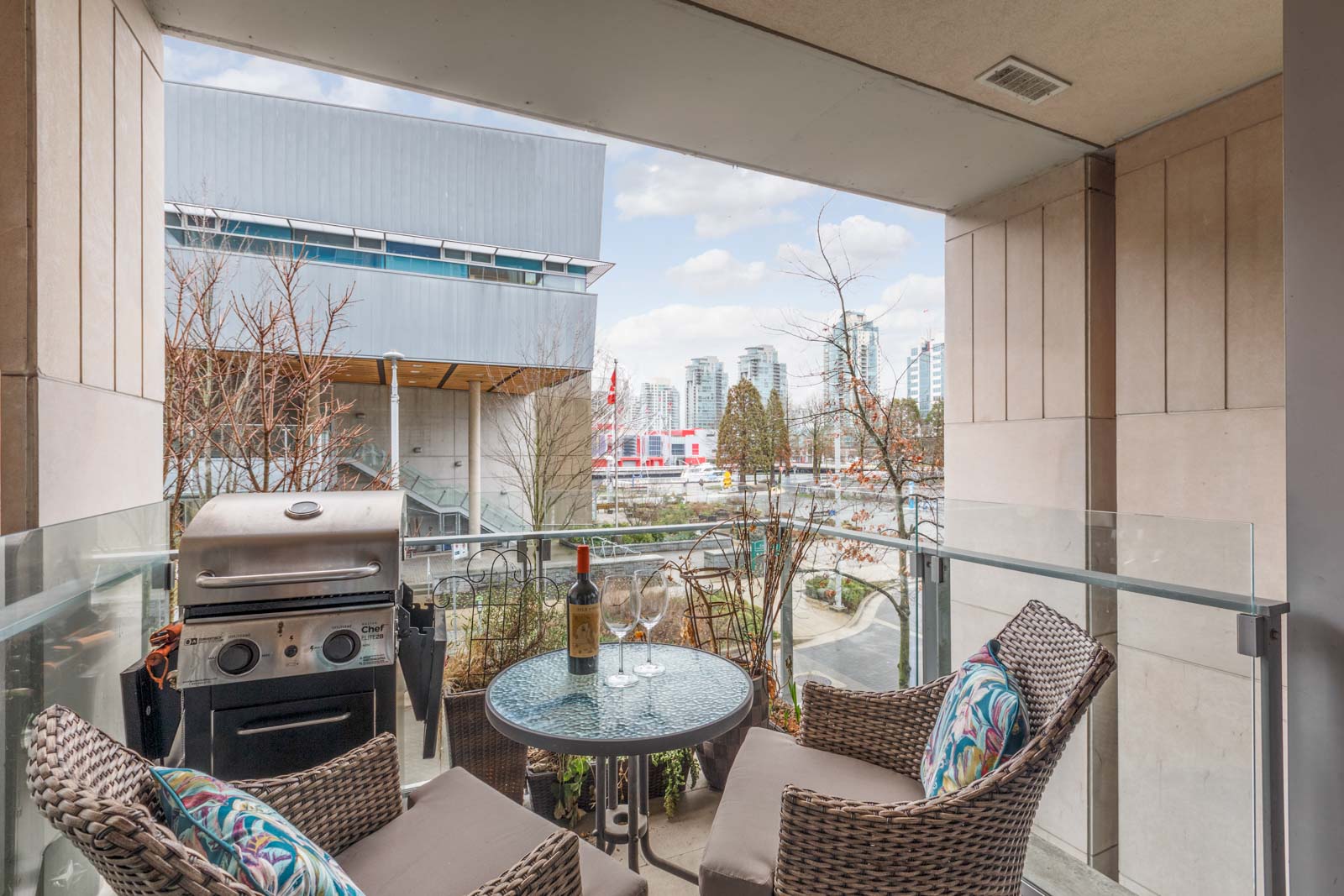 condo patio with table chairs and bbq with view of white building across the street in olympic village vancouver vancouver