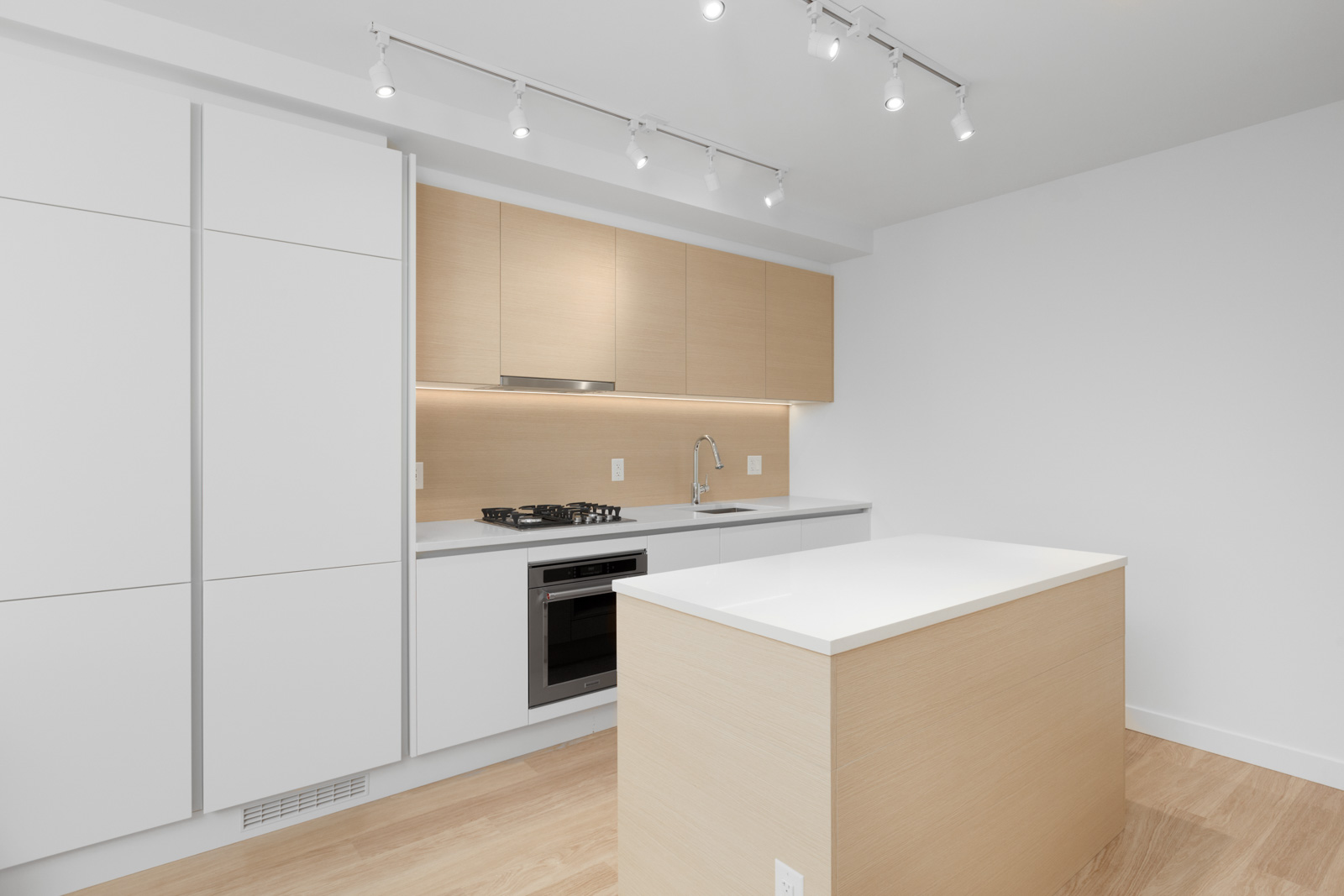 diagonal view of condo kitchen with island and white countertop and cabinets overhead