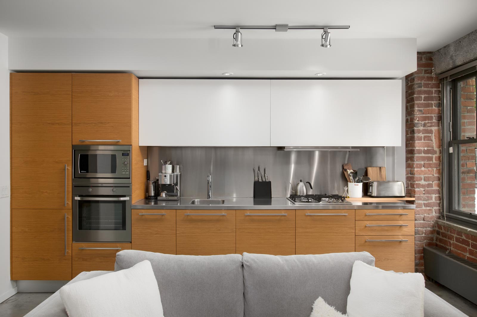 spacious kitchen with modern high-end appliances such as stainless steel sink, fridge, stove, oven, and microwave with sleek cabinet storage and ceiling light fixtures in a rental condo provided by Birds Nest Properties in Vancouver