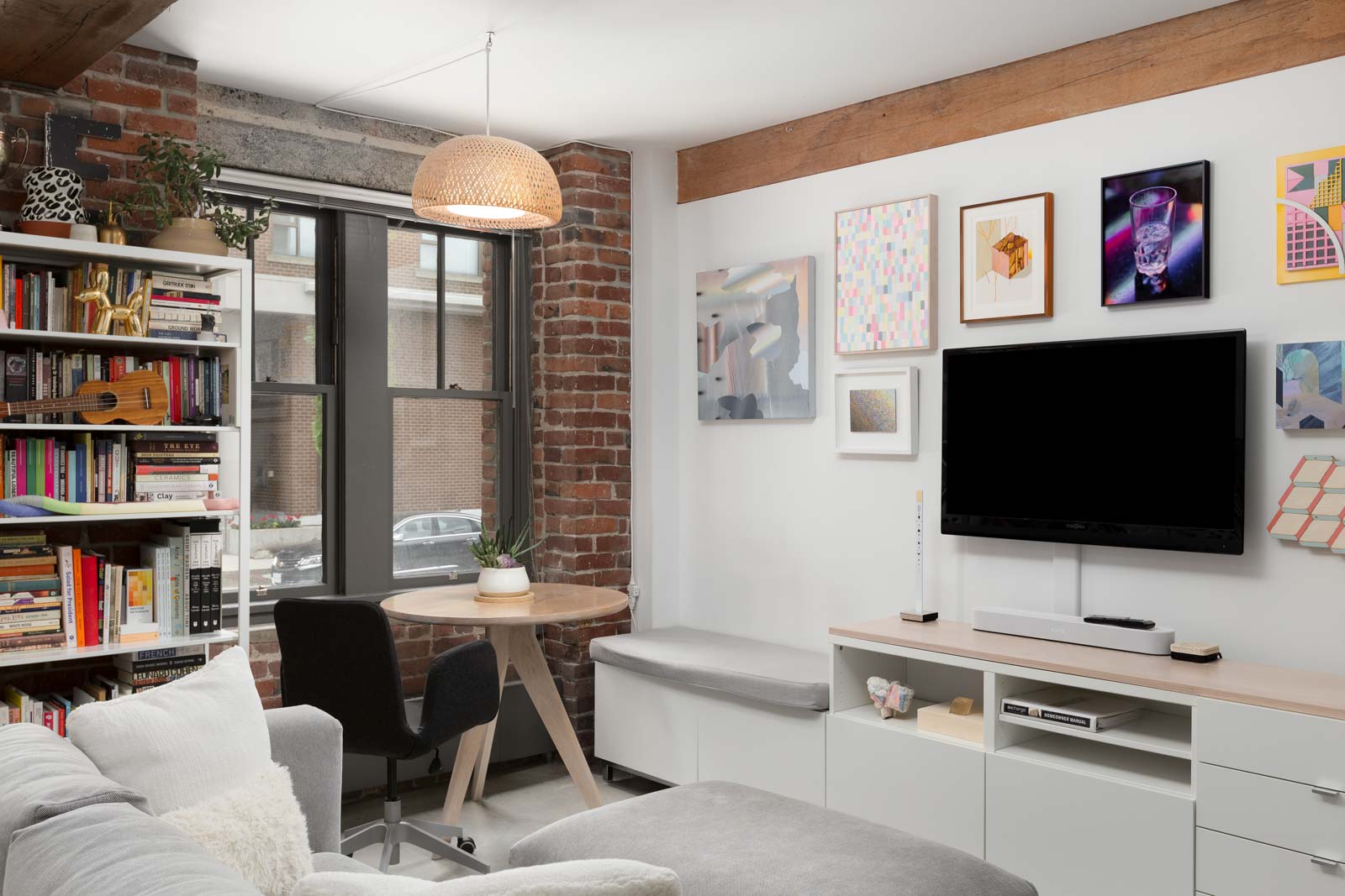 Cozy living space with a coffee nook by the floor-to-ceiling windows and authentic exposed brick in a rental condo provided by Birds Nest Properties in Vancouver