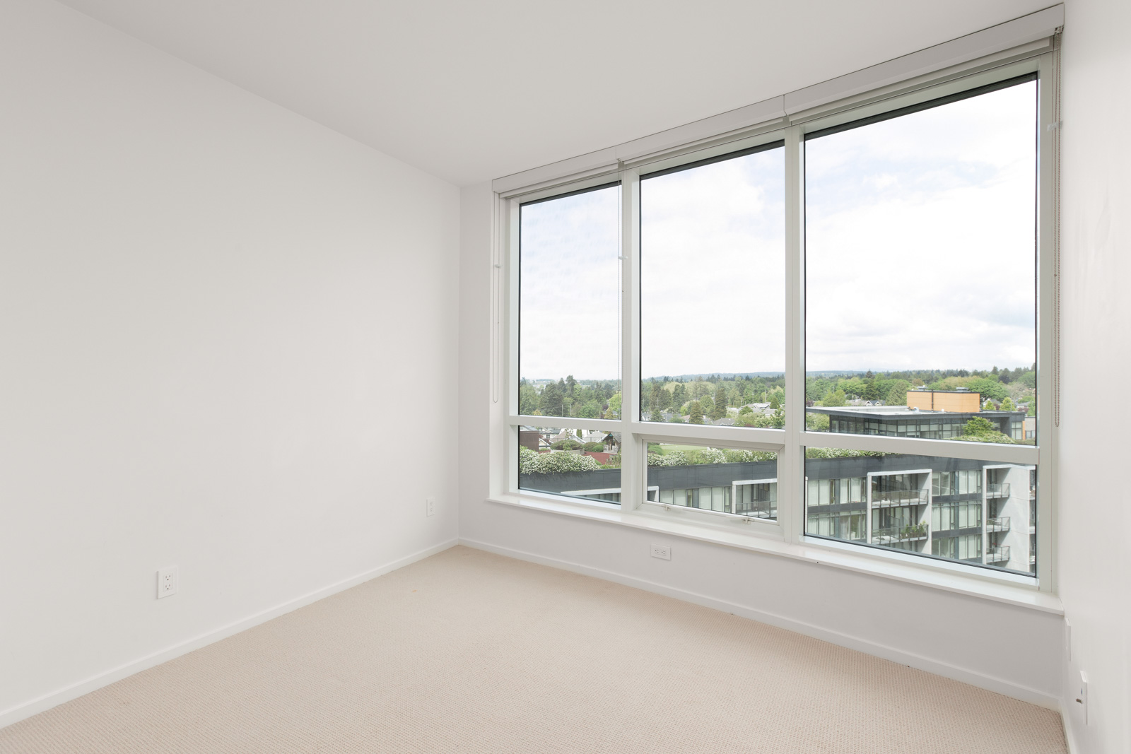 Bedroom with large window providing ample sunlight into the room with carpeted flooring in a rental condo in Vancouver offered by Birds Nest Properties