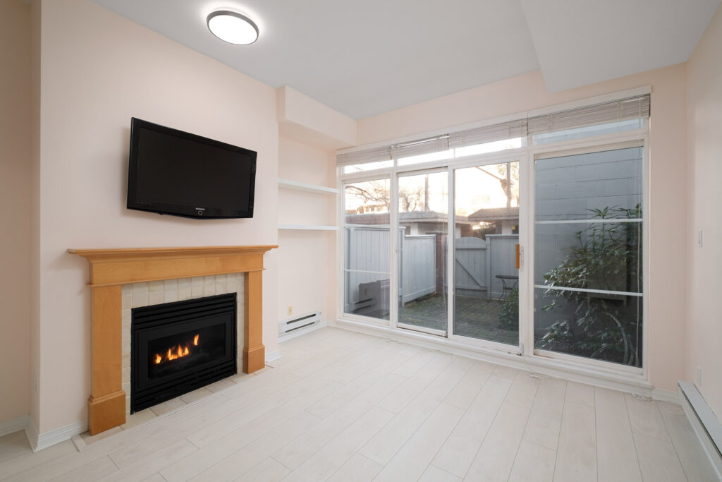 fireplace on right in living room and view to back patio in kitsilano rental townhome managed by birds nest properties