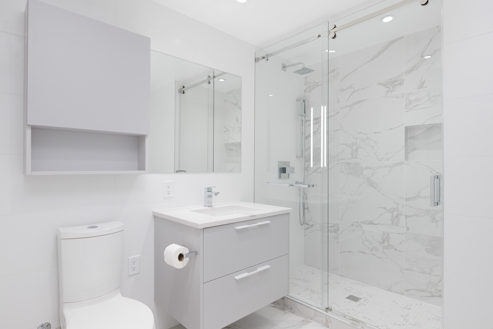 White bathroom with gray cabinets and stand up glass shower at Polaris