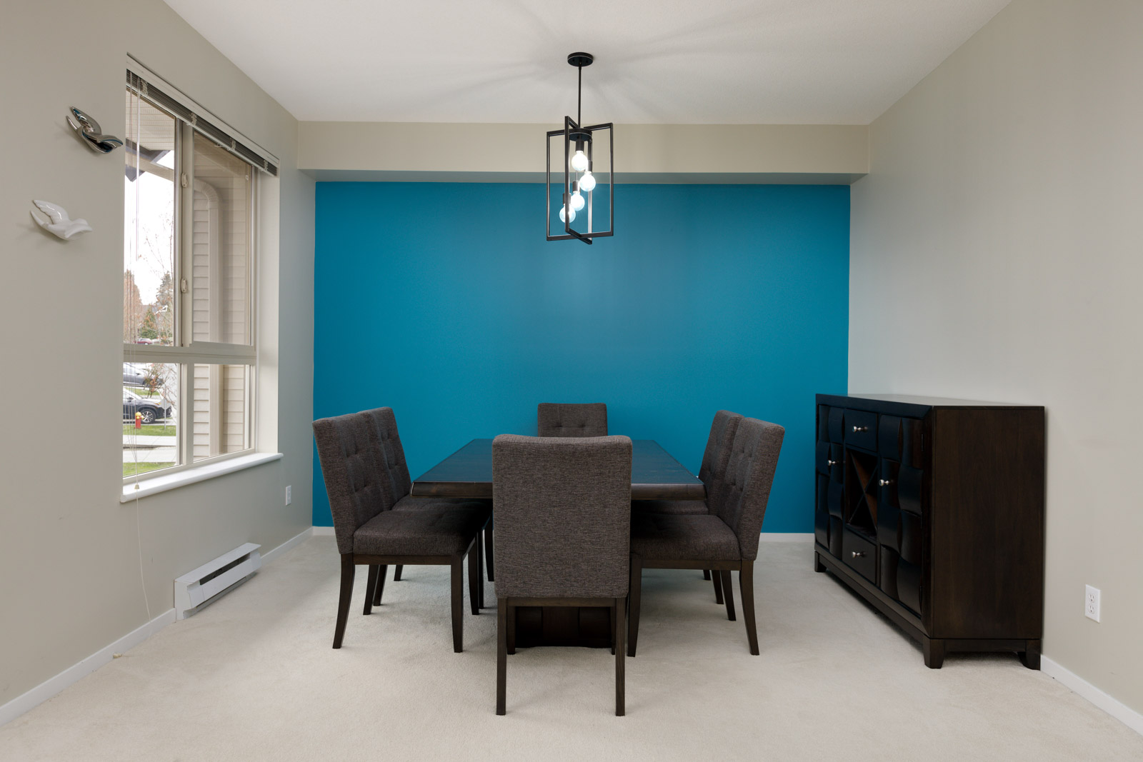 dining room with dark 6 person dining set with a medium blue accent wall and hanging light fixture