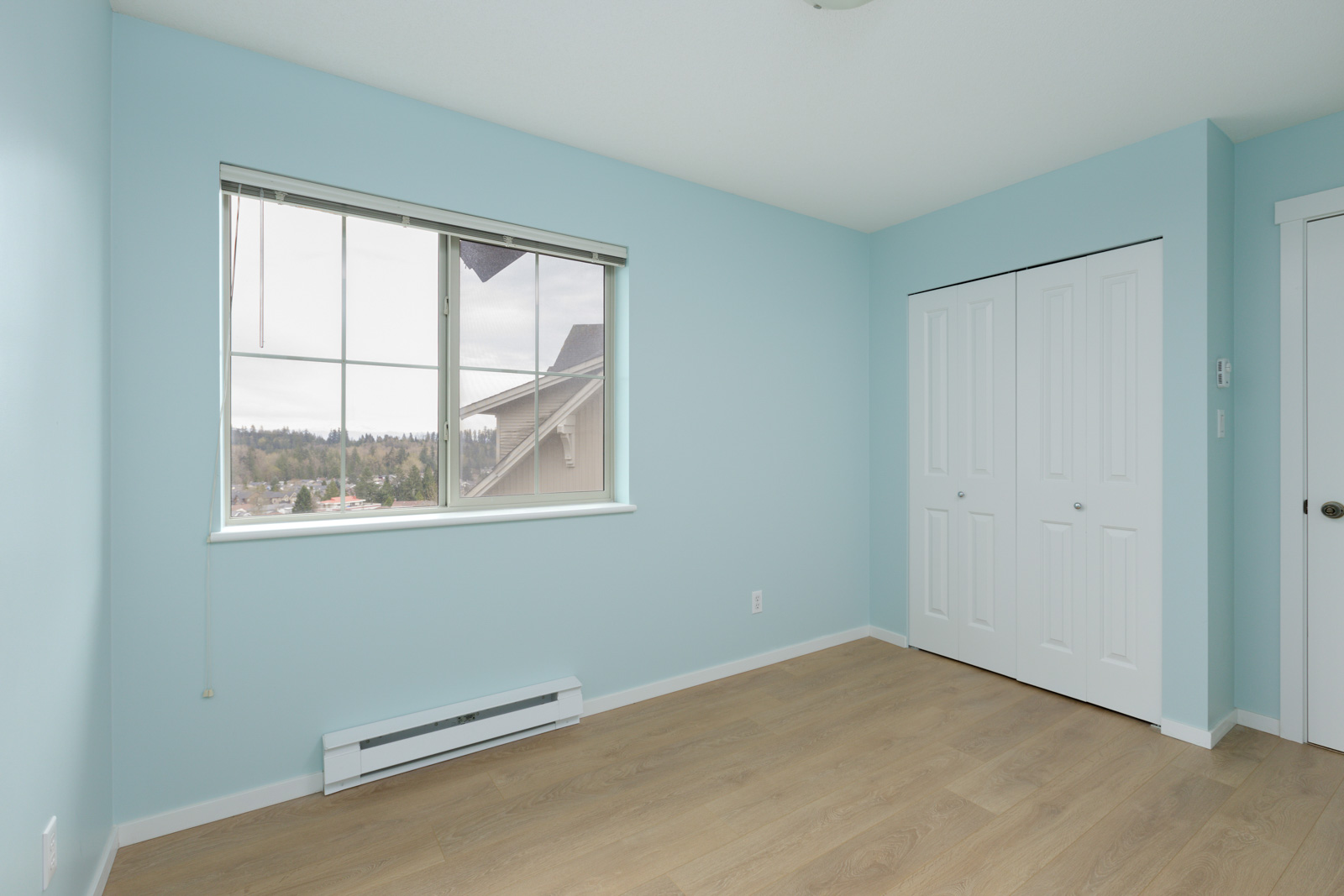 bedroom with baby blue walls, white closet doors and window
