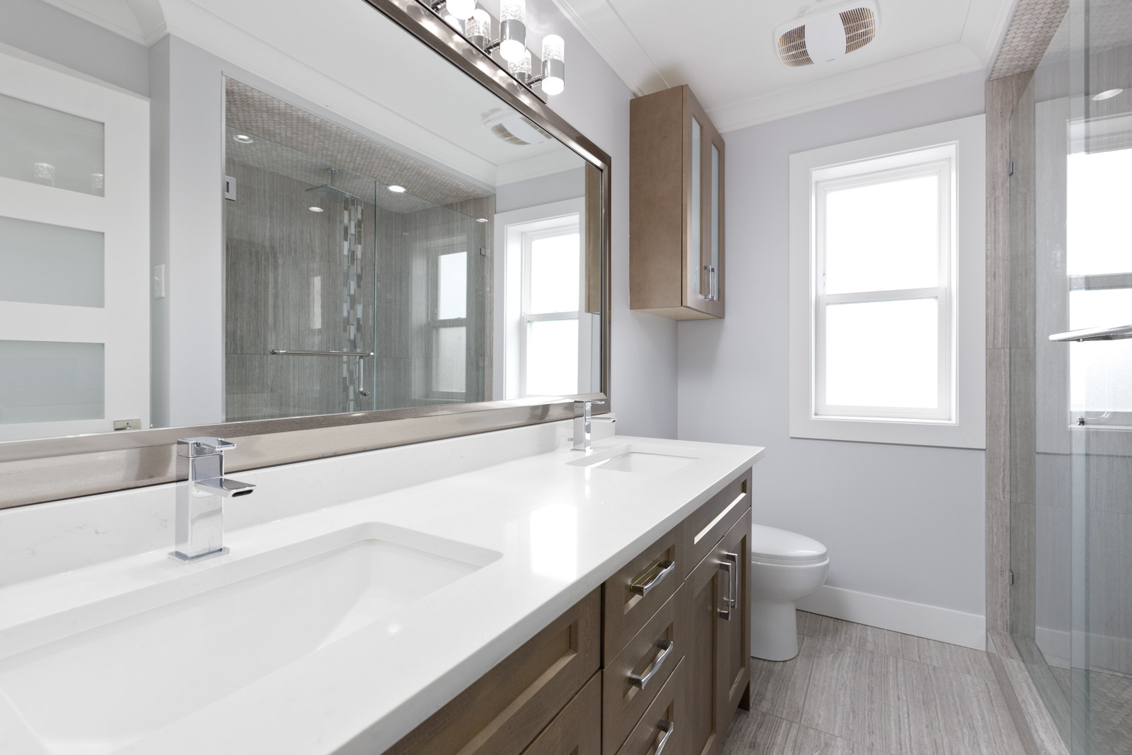 washroom with standing shower and double sink. large mirror and cabinets with drawers