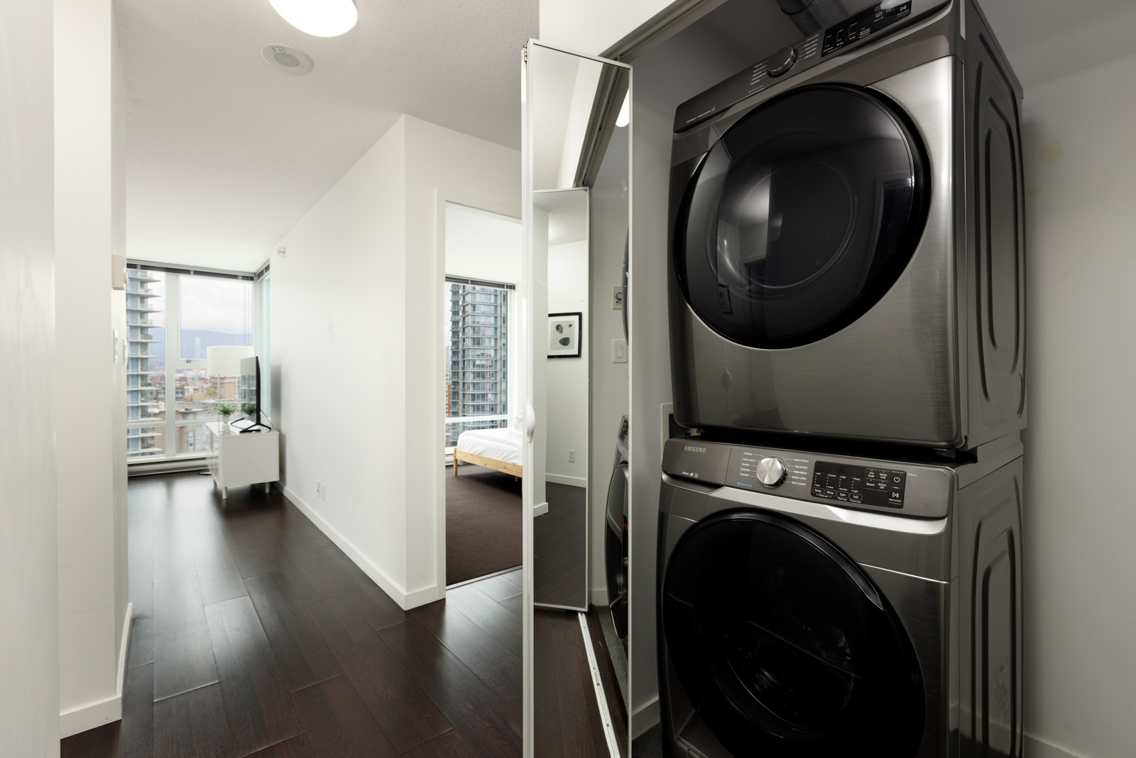 laundry closet with stacking washer and dryer and mirrored door