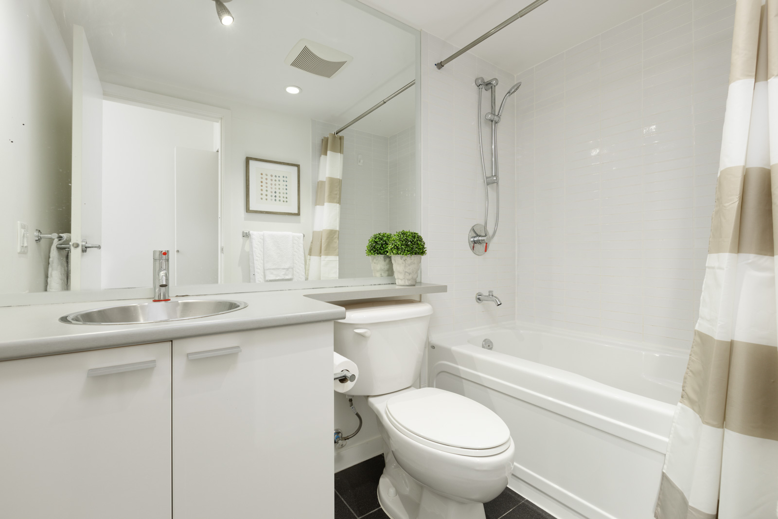 washroom with large mirror, grey counter and white walls