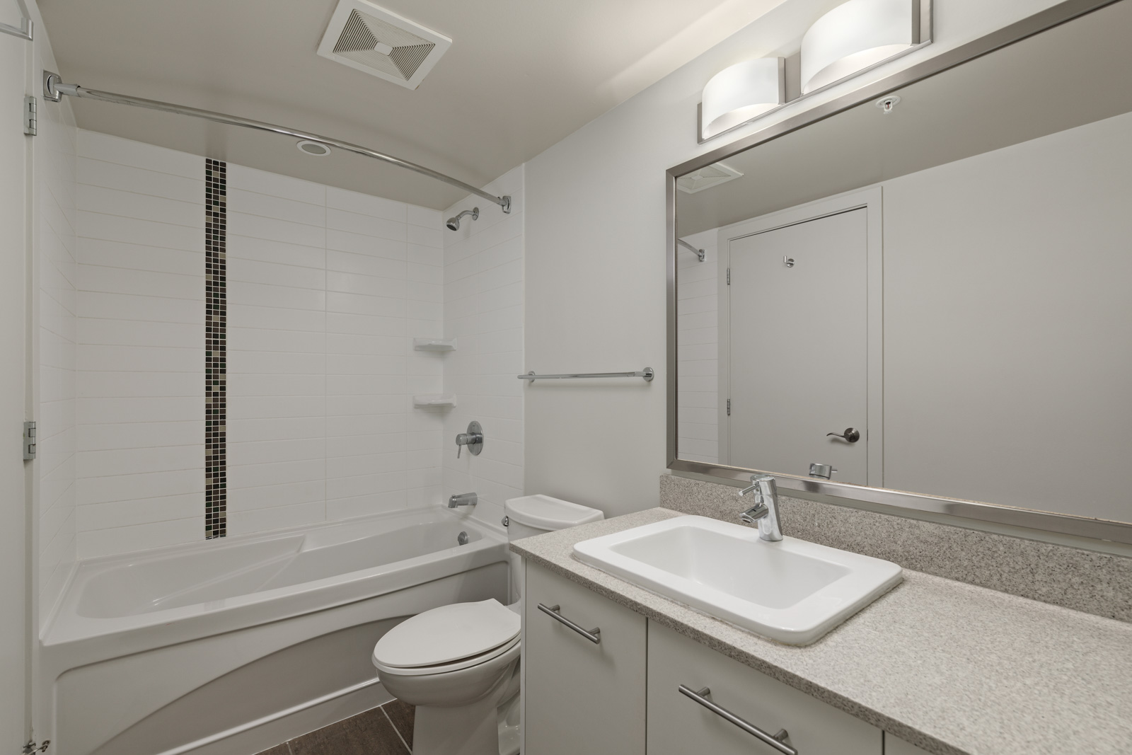 Modern bathroom with a white bathtub-shower combo, wall-mounted shelves, toilet, single-sink vanity, large mirror, and overhead light fixture.