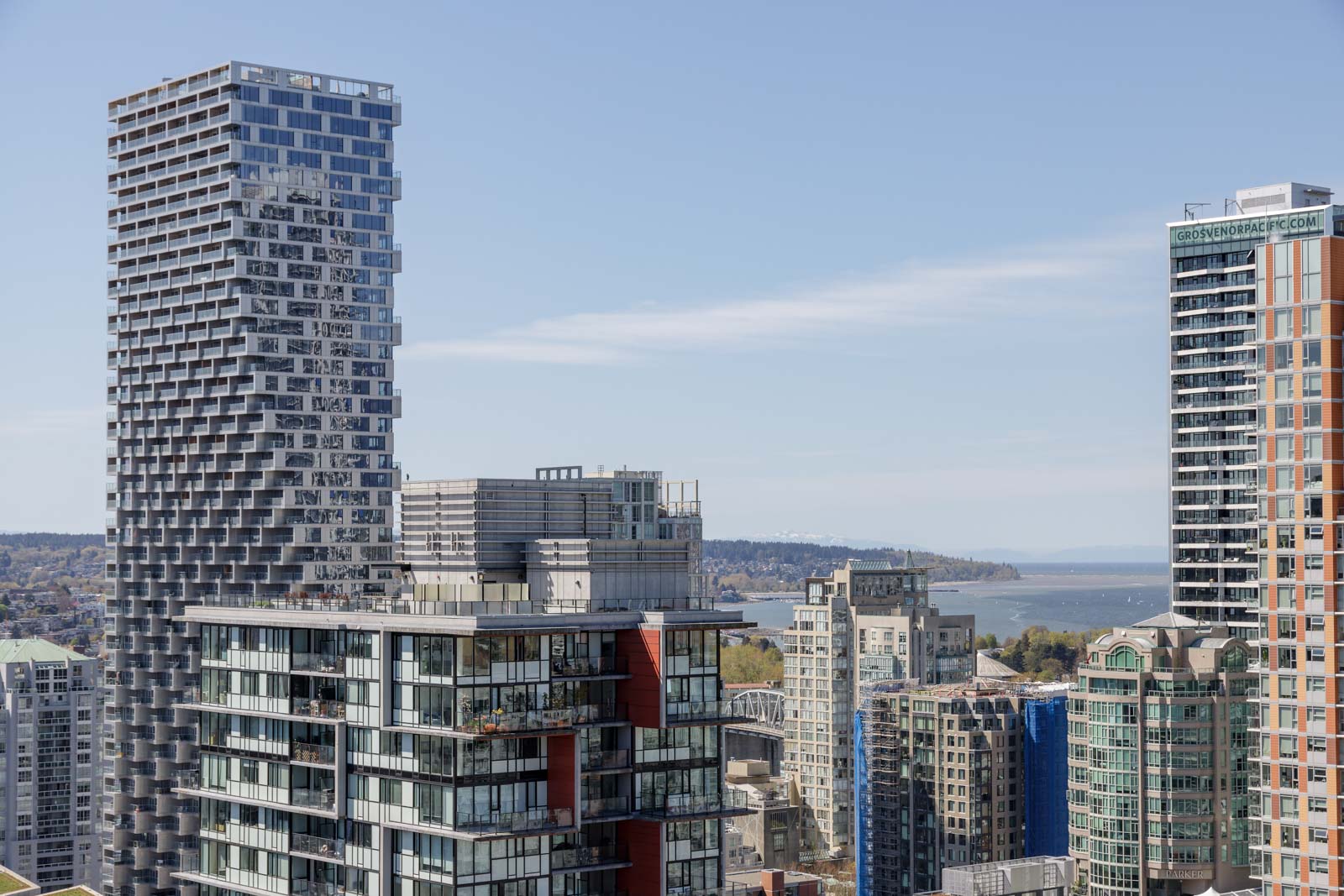 High-rise buildings with modern architecture in a cityscape, with water and land visible in the background under a clear sky.
