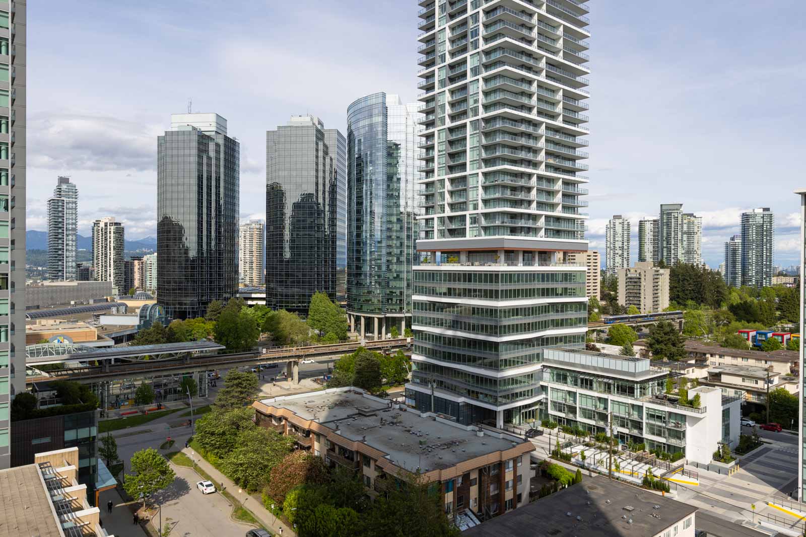 View of modern high-rise buildings and skyscrapers in a cityscape, with roads, greenery, and a mix of residential and commercial structures.