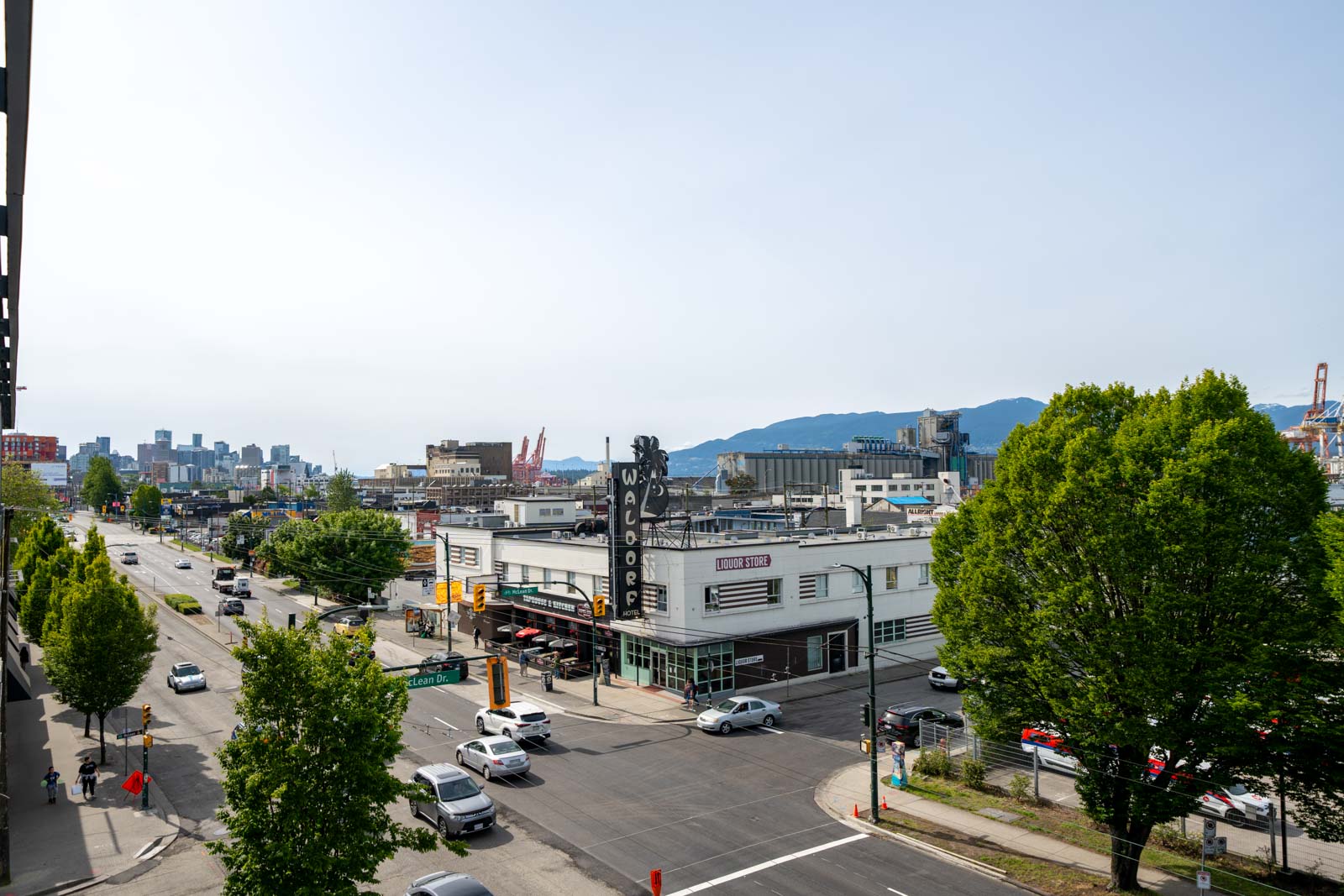Urban street intersection with cars, trees, and a white building labeled 