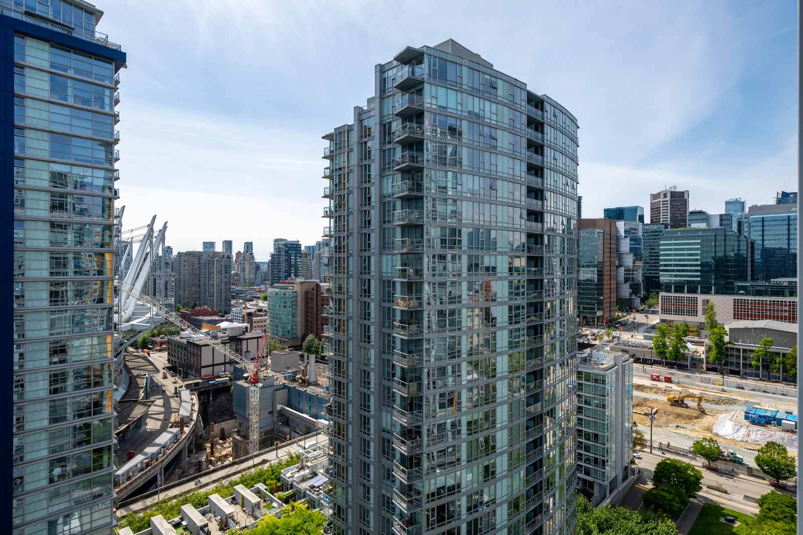 High-rise modern glass apartment buildings in an urban cityscape, with construction and other commercial buildings visible in the background.