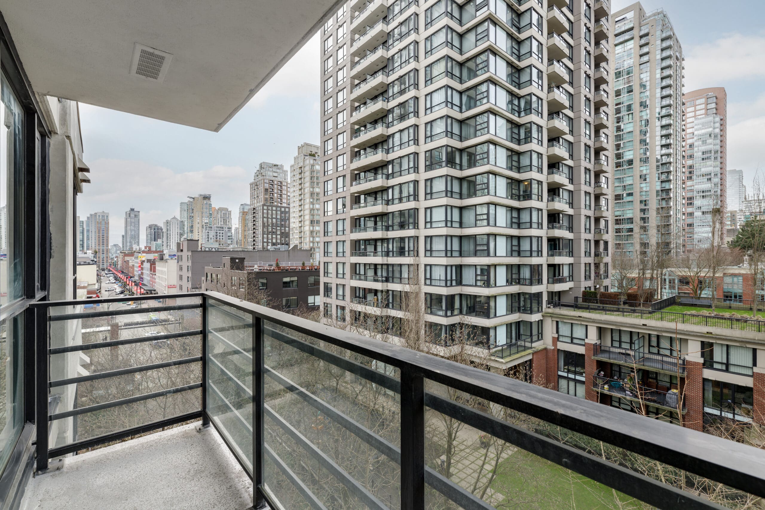 View from a balcony overlooking a cityscape with multiple high-rise apartment buildings and streets below on an overcast day.