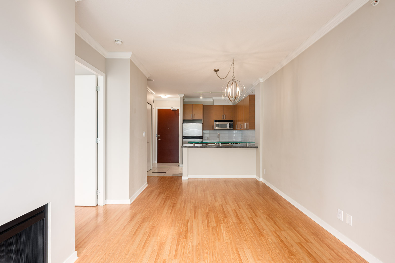 Unfurnished apartment with wood flooring, an open living area, a kitchen with stainless steel appliances, and neutral-colored walls.