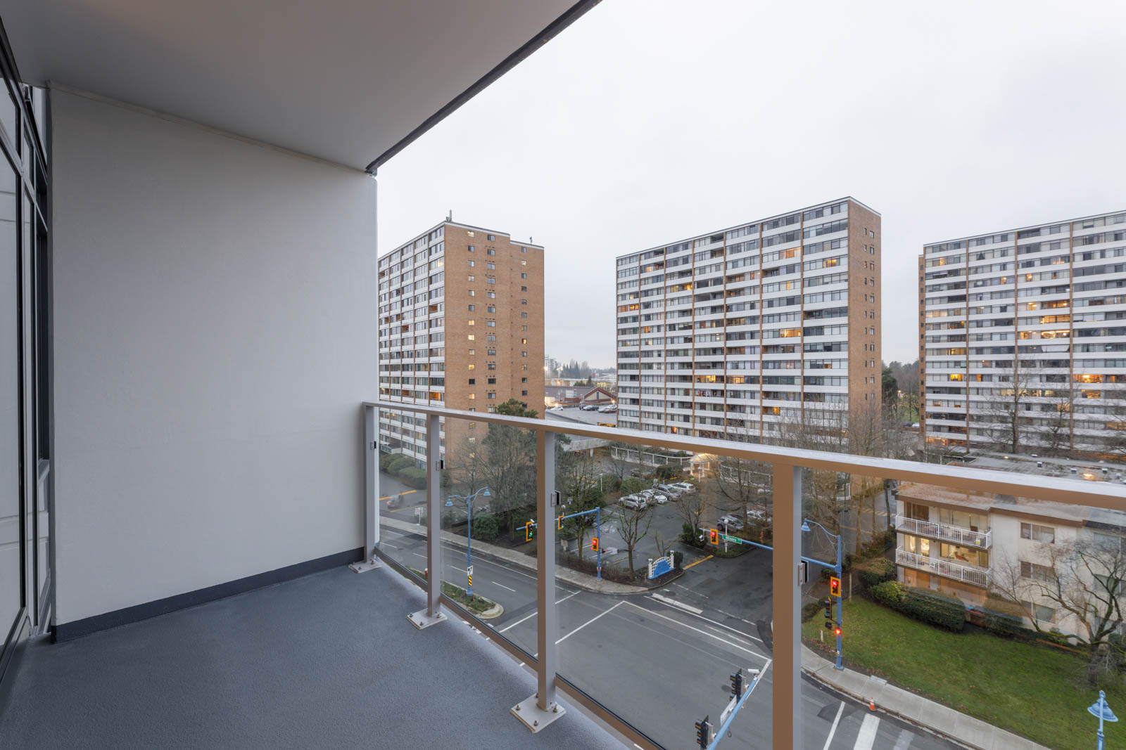 View from a balcony overlooking an intersection with several high-rise apartment buildings in the background on a cloudy day.