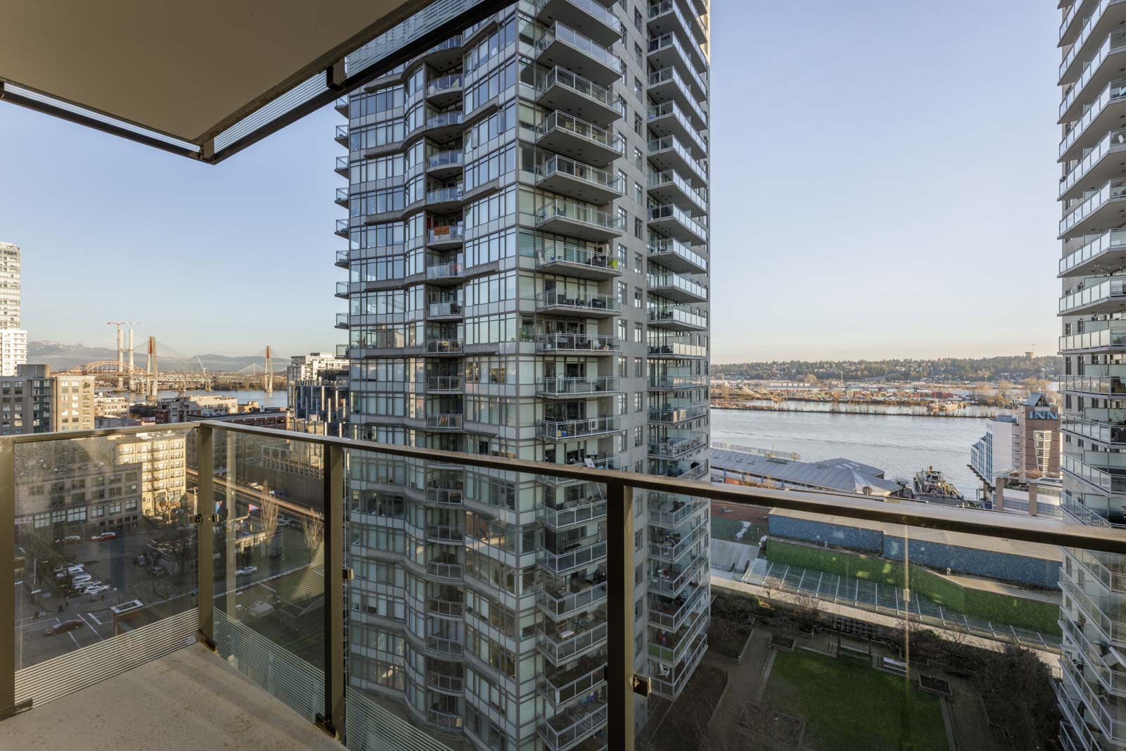 View from a balcony overlooking high-rise buildings, a river, and cityscape under clear sky during daytime.