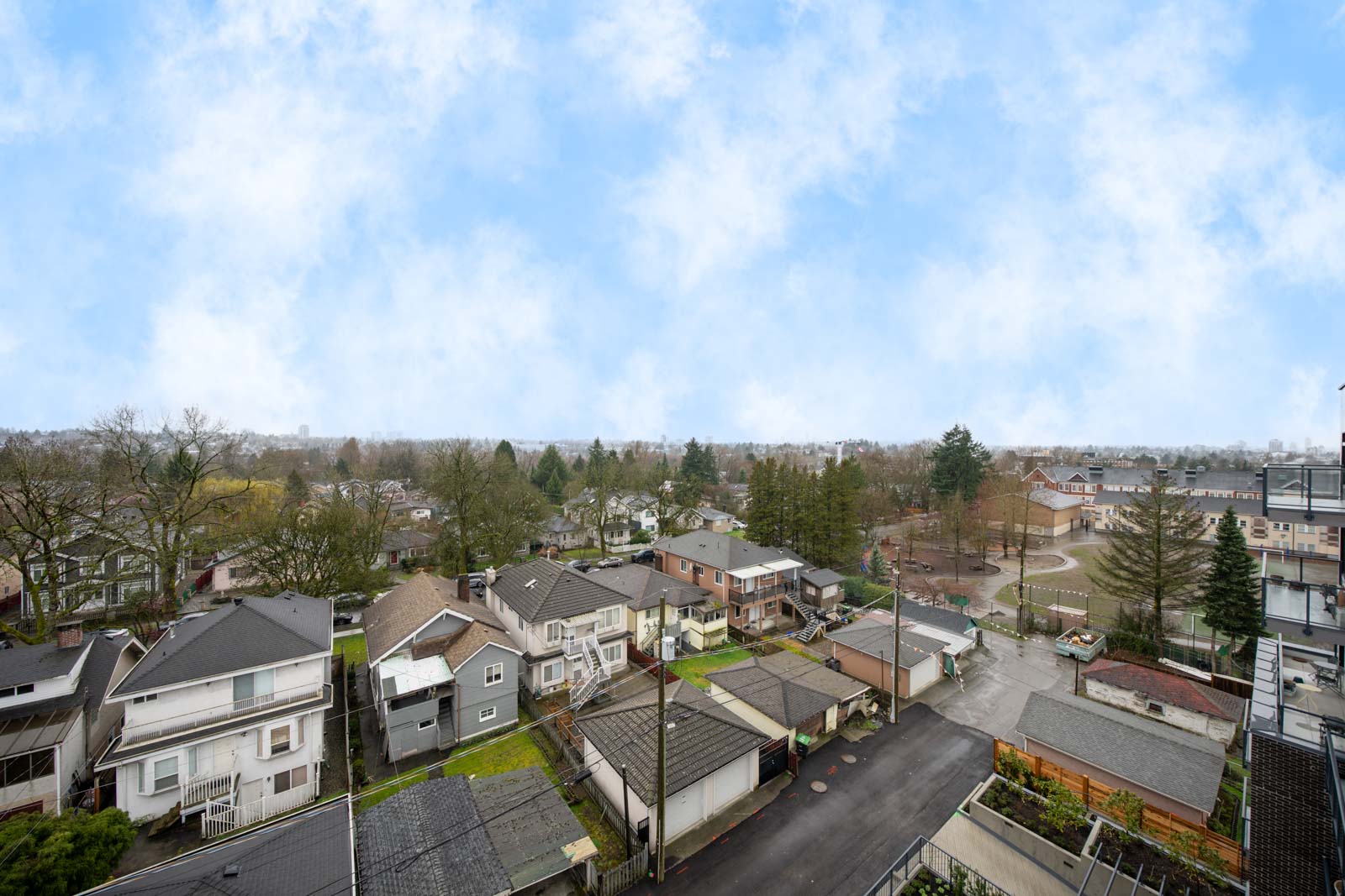 Aerial view of a suburban neighborhood with houses, trees, and streets under a partly cloudy sky.