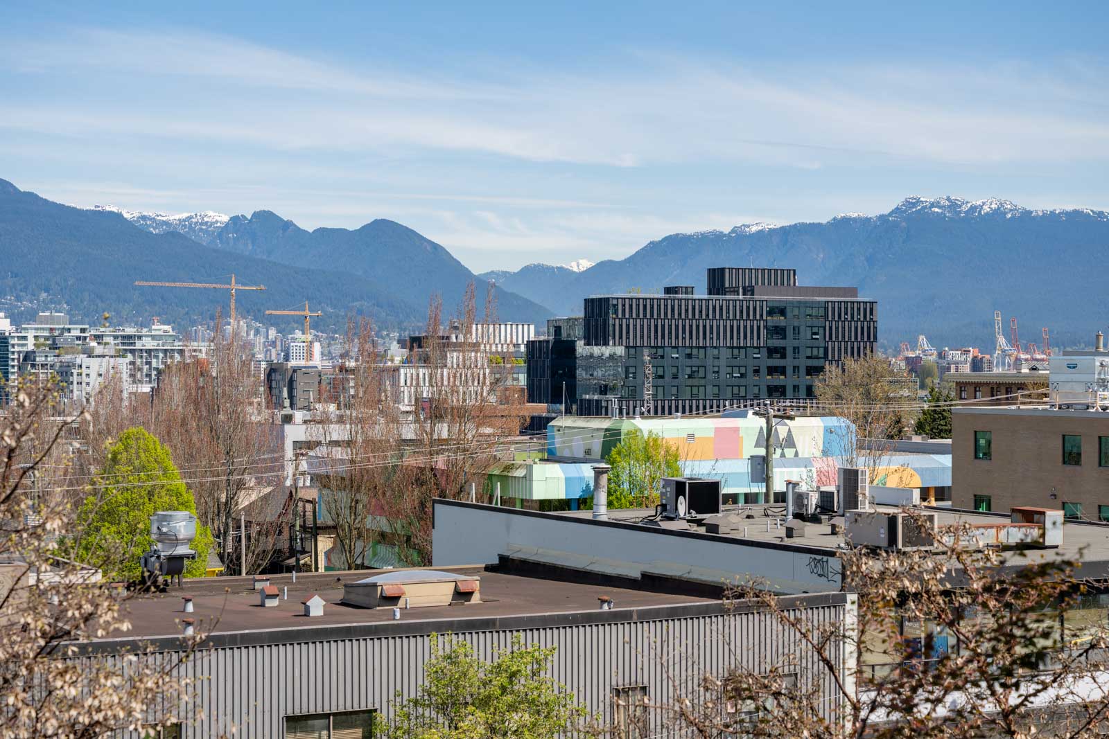City buildings and rooftops with mountains in the background under a clear blue sky.
