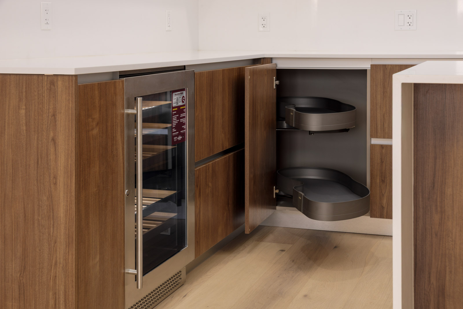 Modern kitchen with wood cabinets, a built-in glass-front wine cooler, and an open corner cabinet with two pull-out shelves.