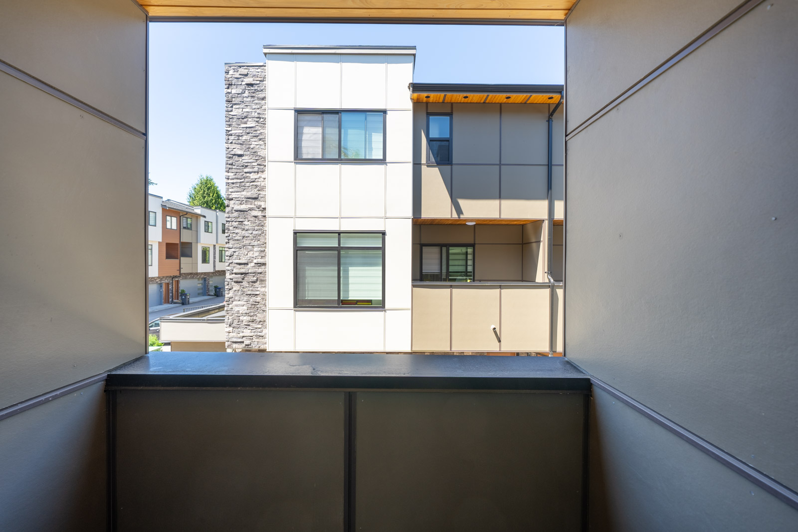 View from a covered balcony looking out at modern townhouses with large windows and neutral-colored exteriors.