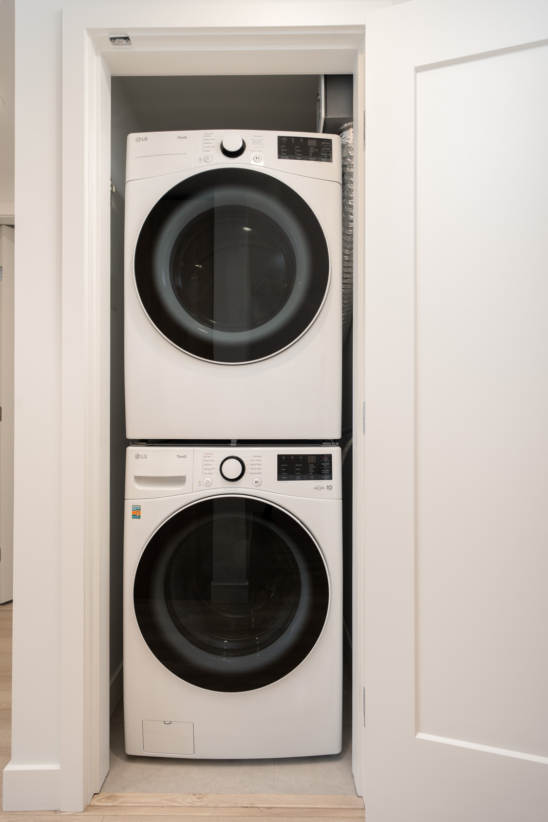 A stacked washer and dryer set is installed in a small, white closet with the door open.