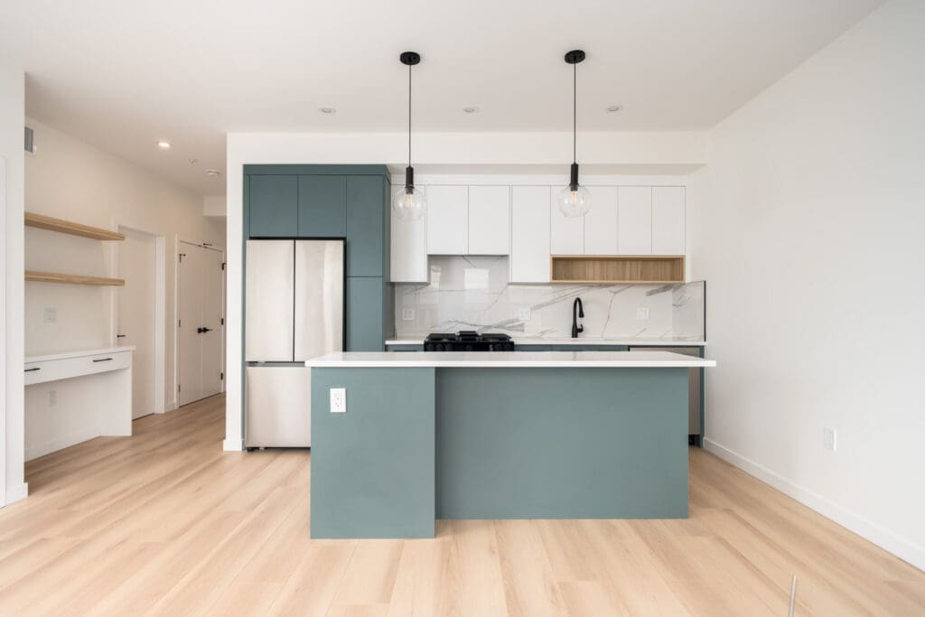 Modern kitchen with teal and white cabinets, stainless steel appliances, pendant lights, light wood flooring, and open shelves.