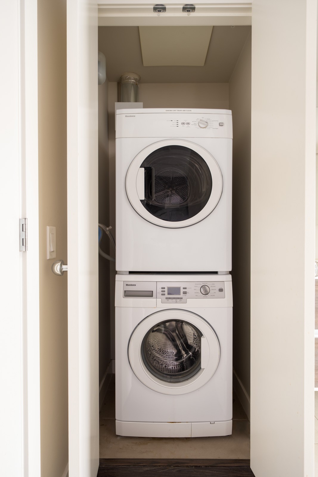 A stacked washer and dryer set is installed inside a small closet with white doors.