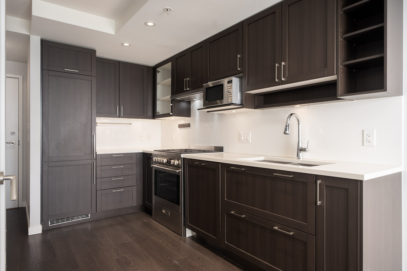 Modern kitchen with dark cabinets, white countertops, stainless steel appliances, and bright lighting in a Boundary Rd Vancouver home.