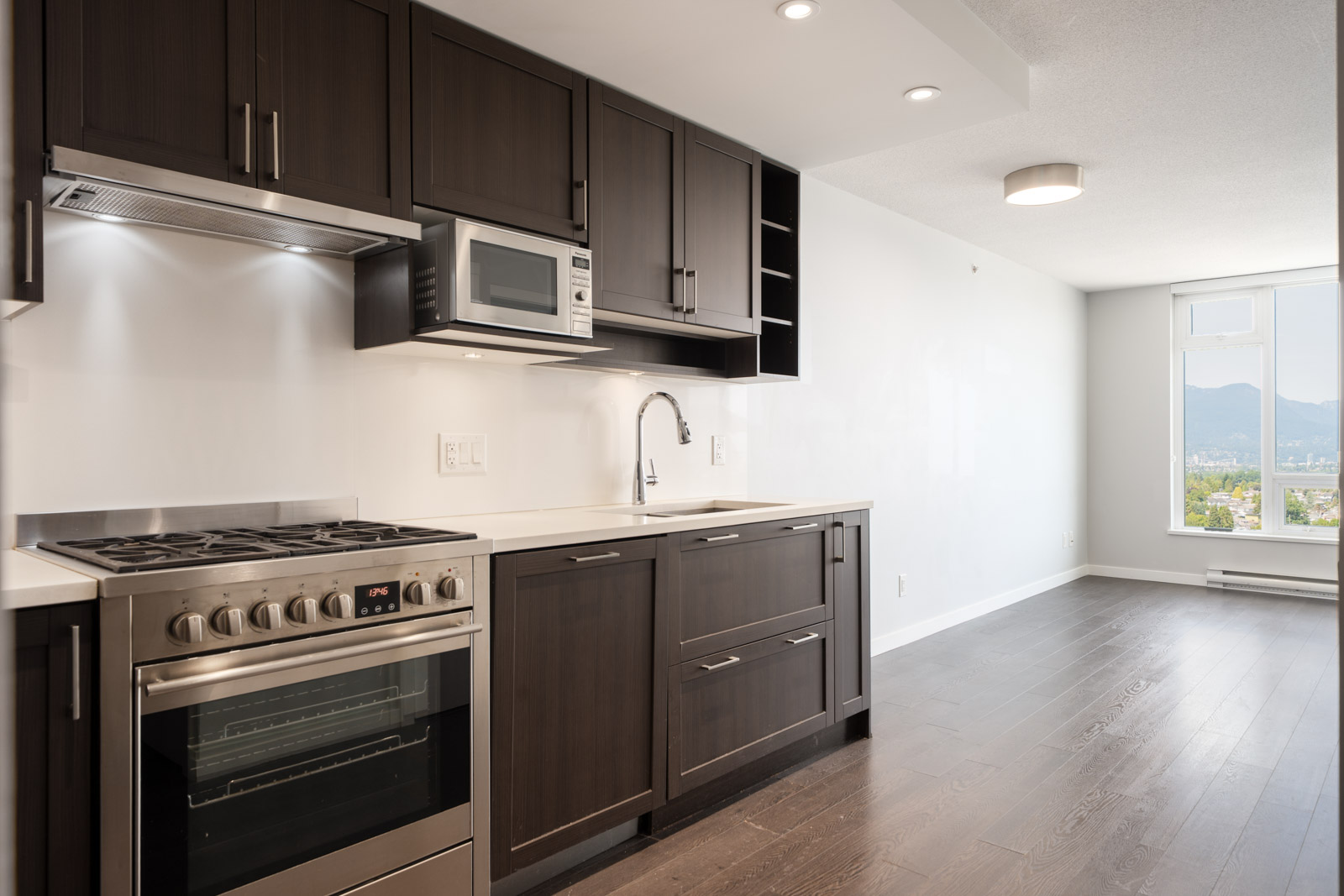 Modern kitchen with dark wood cabinets, stainless appliances, white counters, and a window view of Vancouver near Boundary Rd.