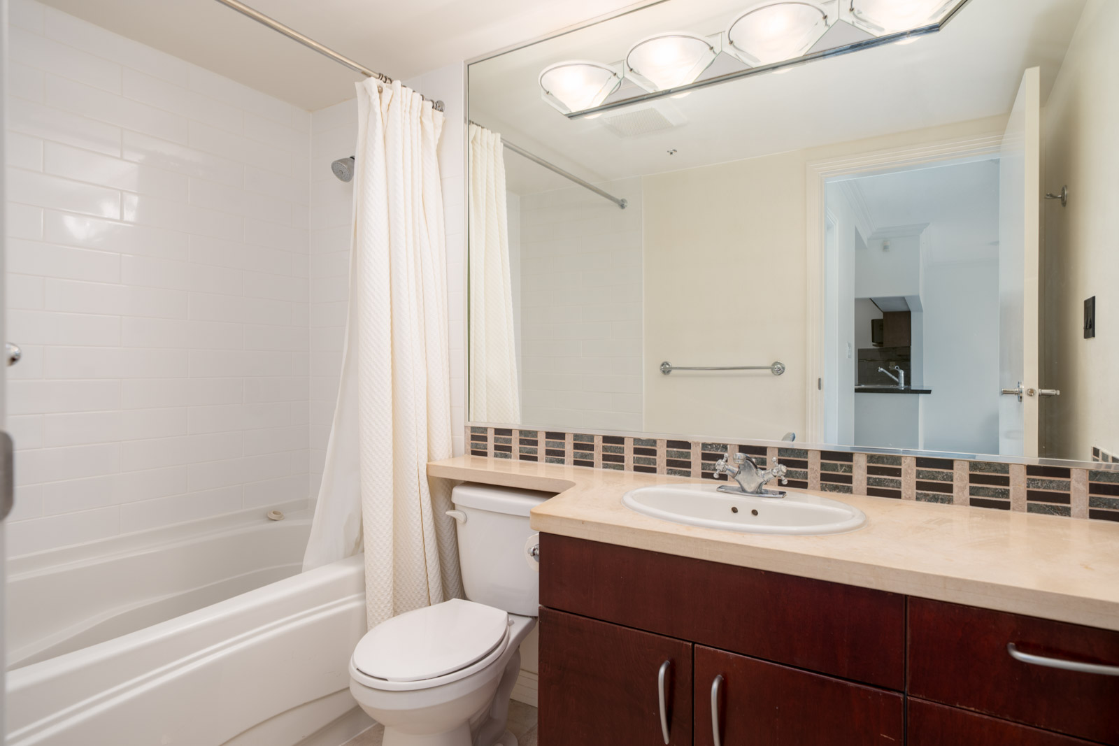 Contemporary Vancouver bathroom at 189 Davie St. with a bathtub, shower, white curtain, toilet, mirror, and dark wood vanity.