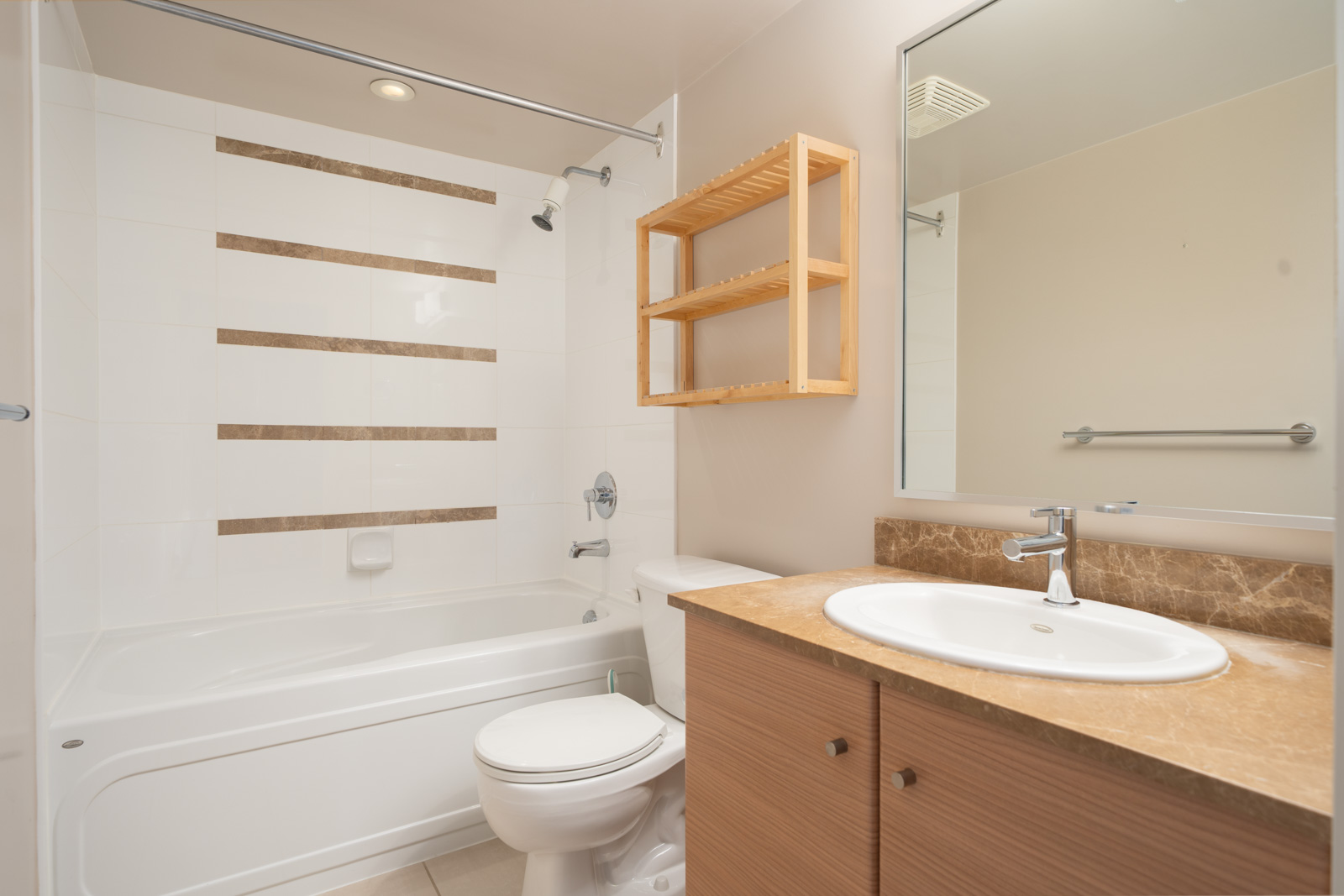 Modern bathroom on 23rd Floor, Mainland St, Vancouver; bathtub-shower combo, toilet, wood vanity and shelf, white tiles, brown accents.
