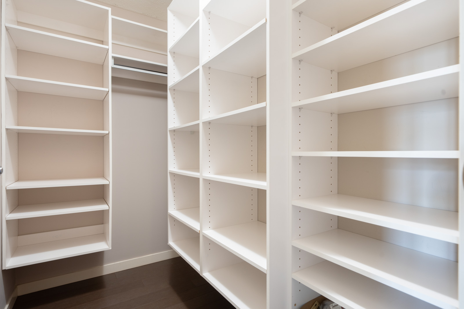 Walk-in closet at 909 Mainland St, Vancouver, featuring white built-in shelves and a dark wood floor, shown from inside.