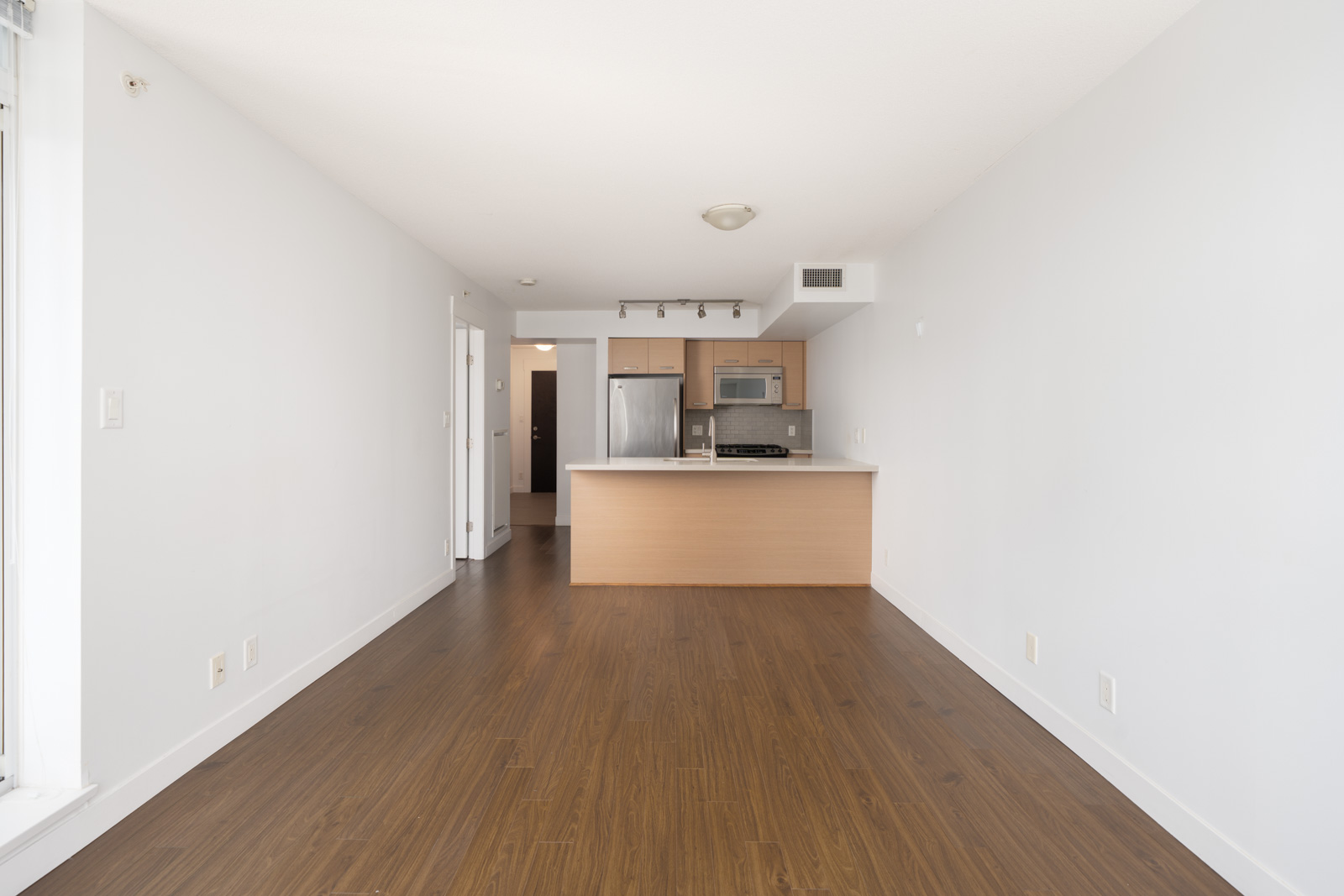 Unfurnished apartment at 8033 Saba Road, Richmond, with wood floors, white walls, and a kitchen with stainless appliances.