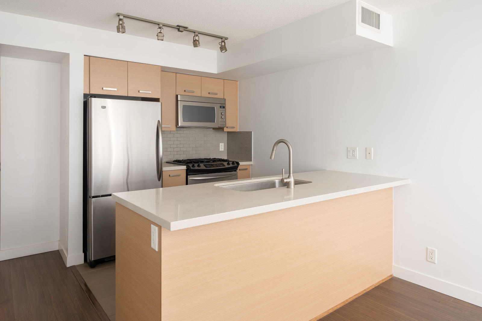 Contemporary kitchen at 8033 Saba Rd, Richmond with light wood cabinets, stainless appliances, island sink, and tile backsplash.