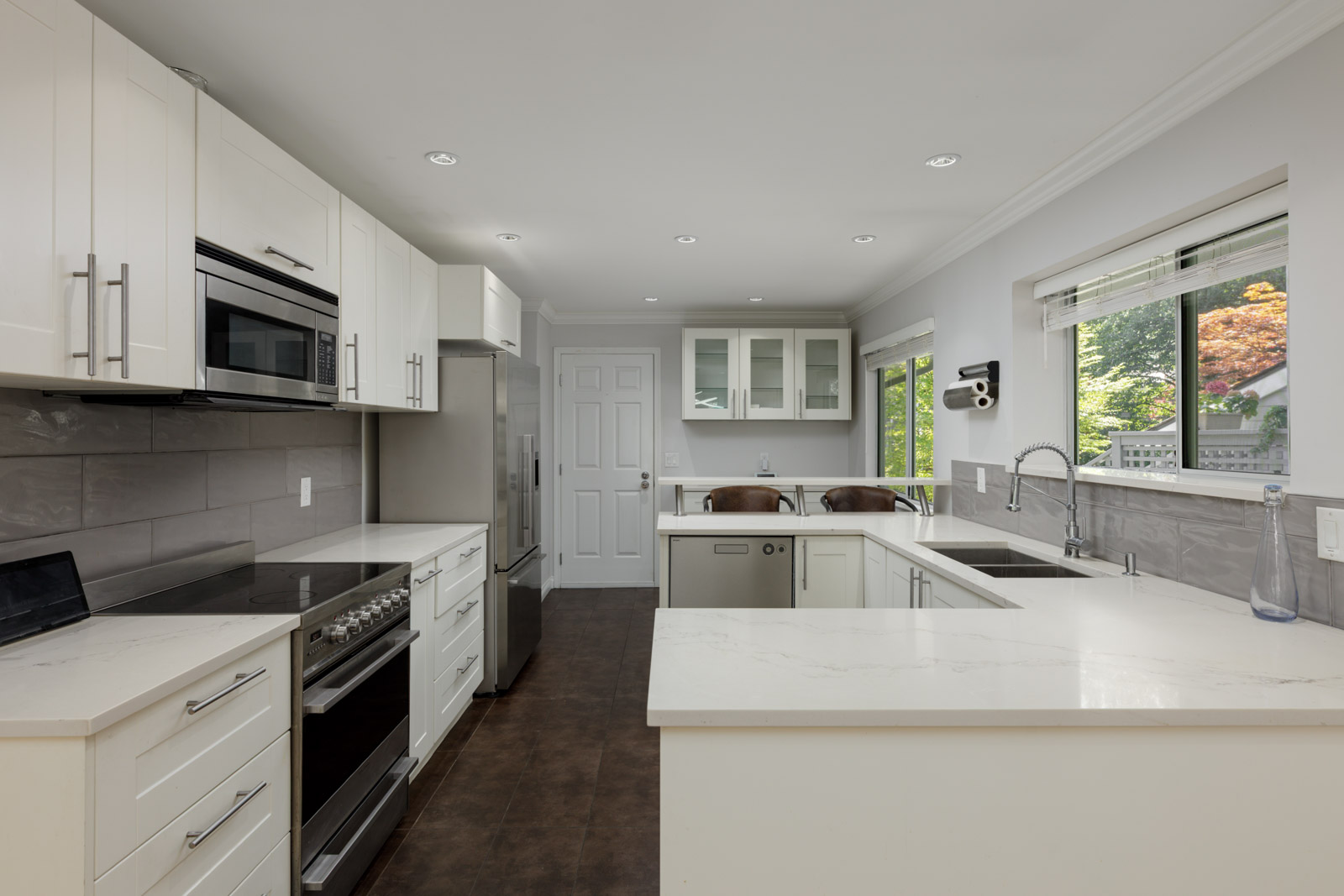 Modern kitchen with white cabinets, stainless steel appliances, double sink, and large windows at 3634 Garibaldi Dr, Vancouver.