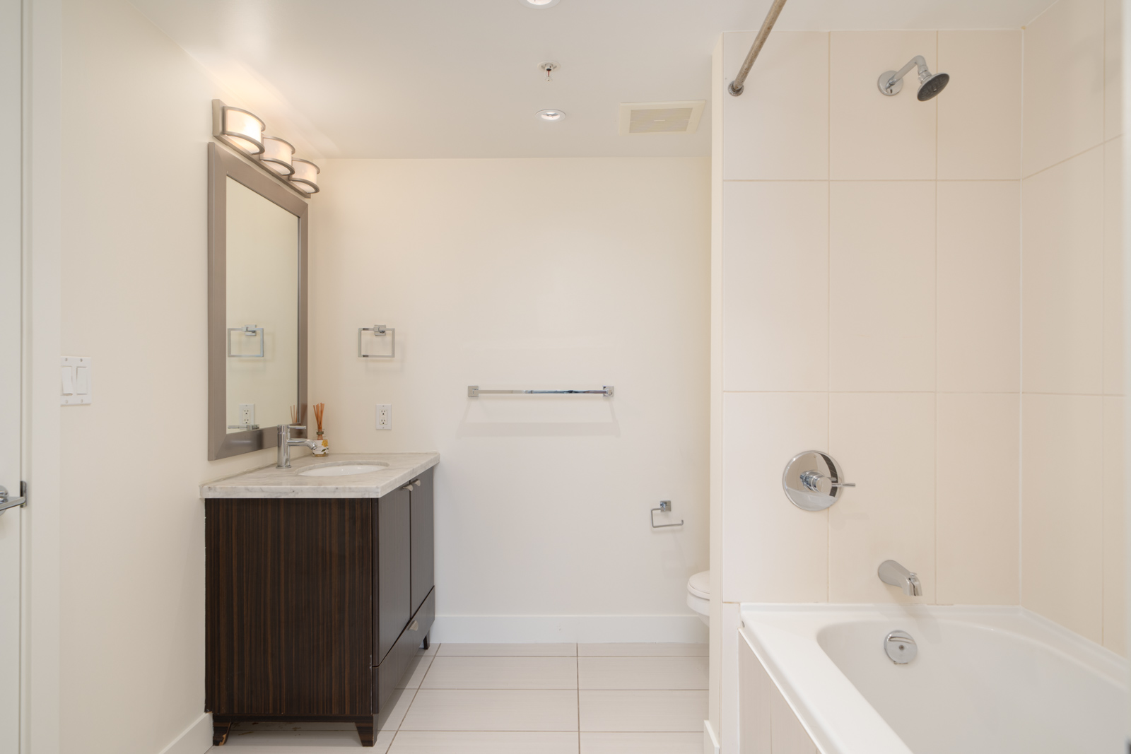 Modern 5th floor bathroom at 160 3rd St W, North Vancouver with vanity and mirror left, toilet center, tub and shower right.