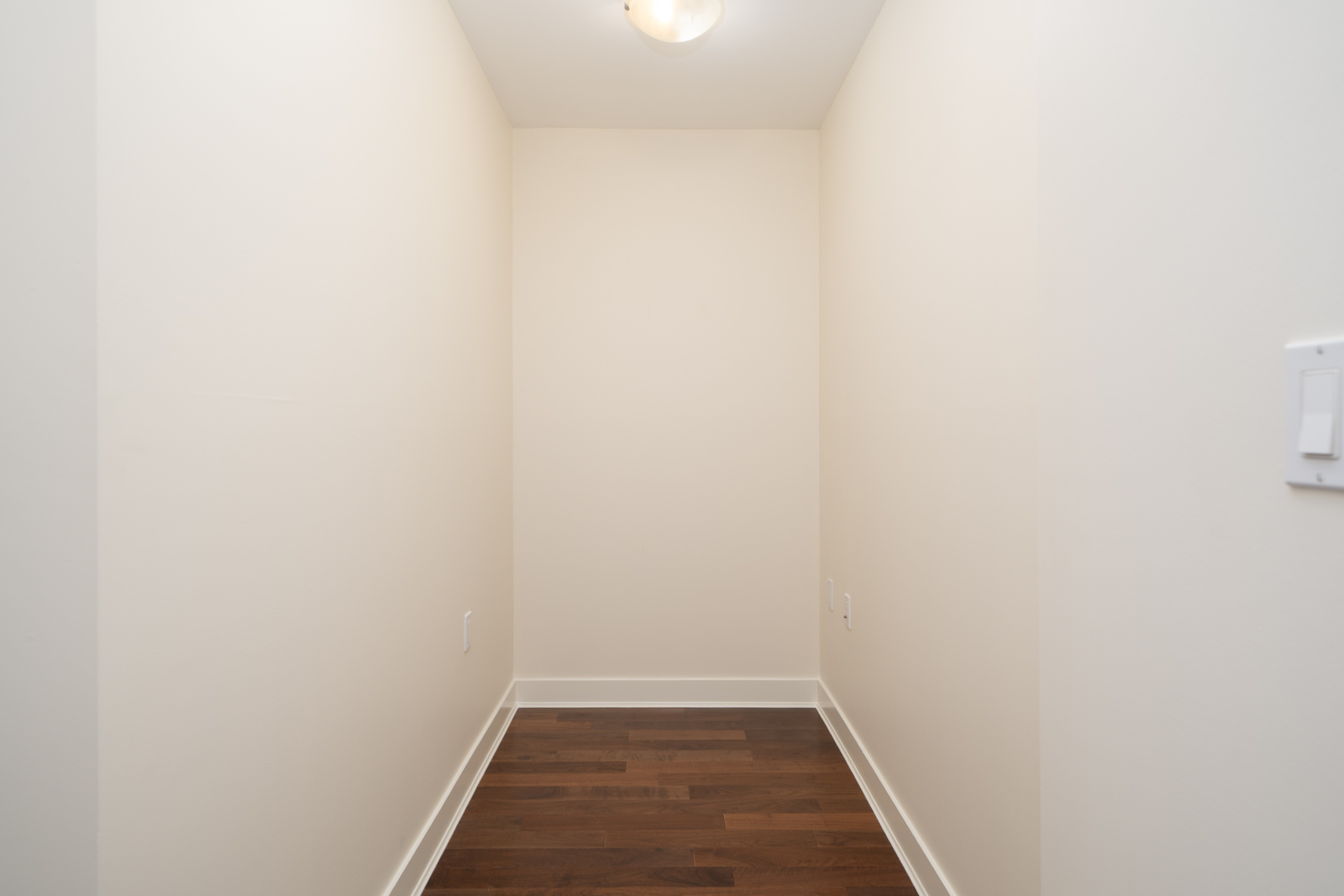 Empty hallway on the 5th floor at 160 3rd St W, North Vancouver, with light walls, dark wood floors, and a ceiling light.