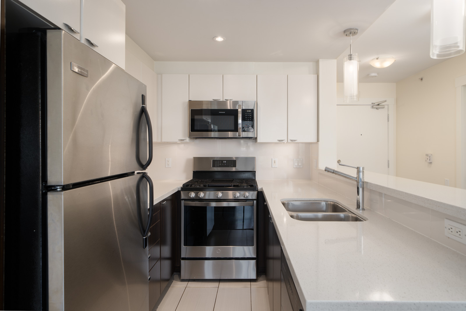 Modern kitchen at 160 3rd St W, North Vancouver with stainless appliances, white cabinets, double sink, and quartz counters.