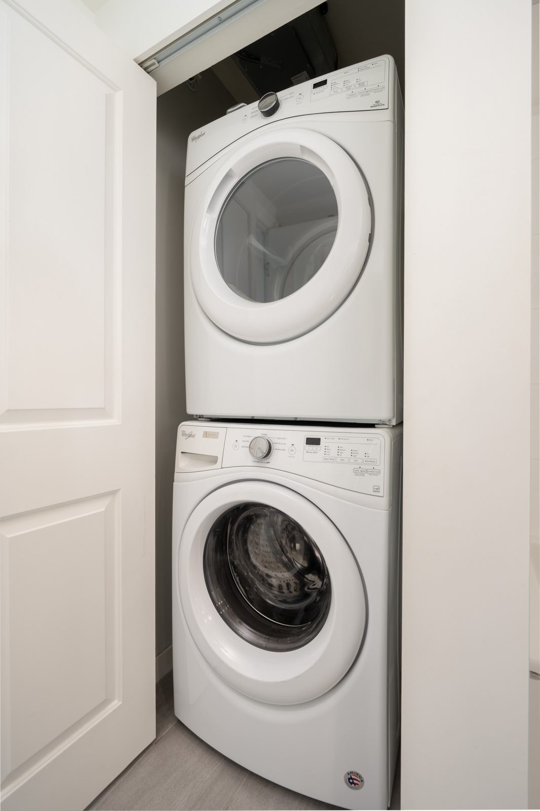 Stacked white washer and dryer in a small closet with a partially open white door at 3281 East Kent Ave N, Vancouver.
