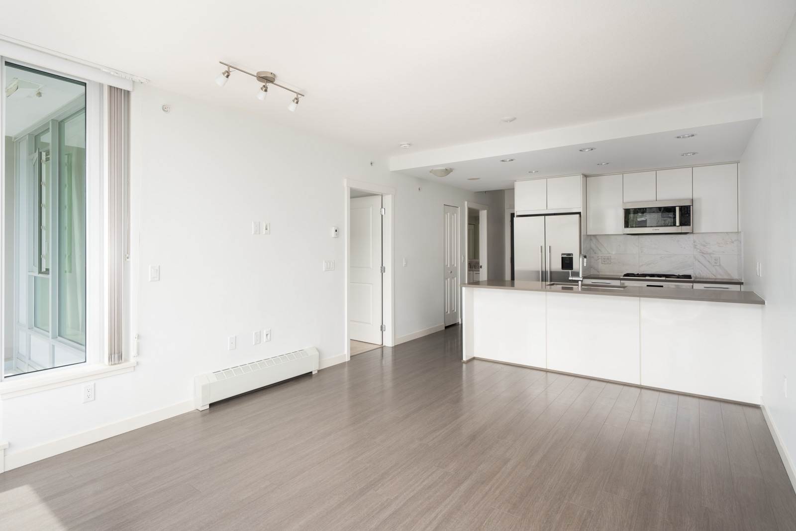 Unfurnished modern apartment, 2nd floor, open kitchen, stainless appliances, light wood floors, large window, East Kent Ave, Vancouver.