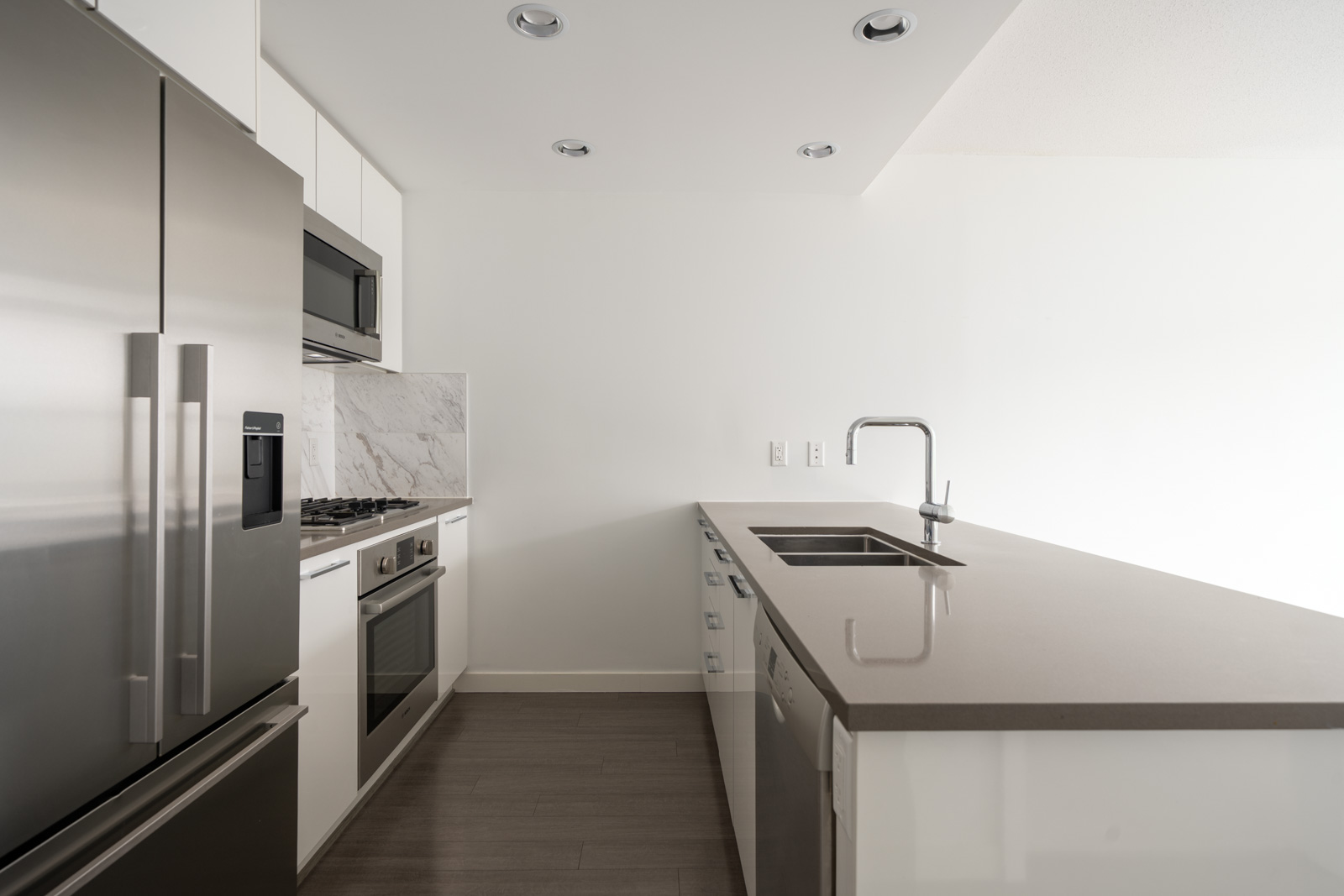 Modern kitchen with stainless appliances, gray counters, built-in oven, and undermount sink. On 2nd floor in Vancouver.