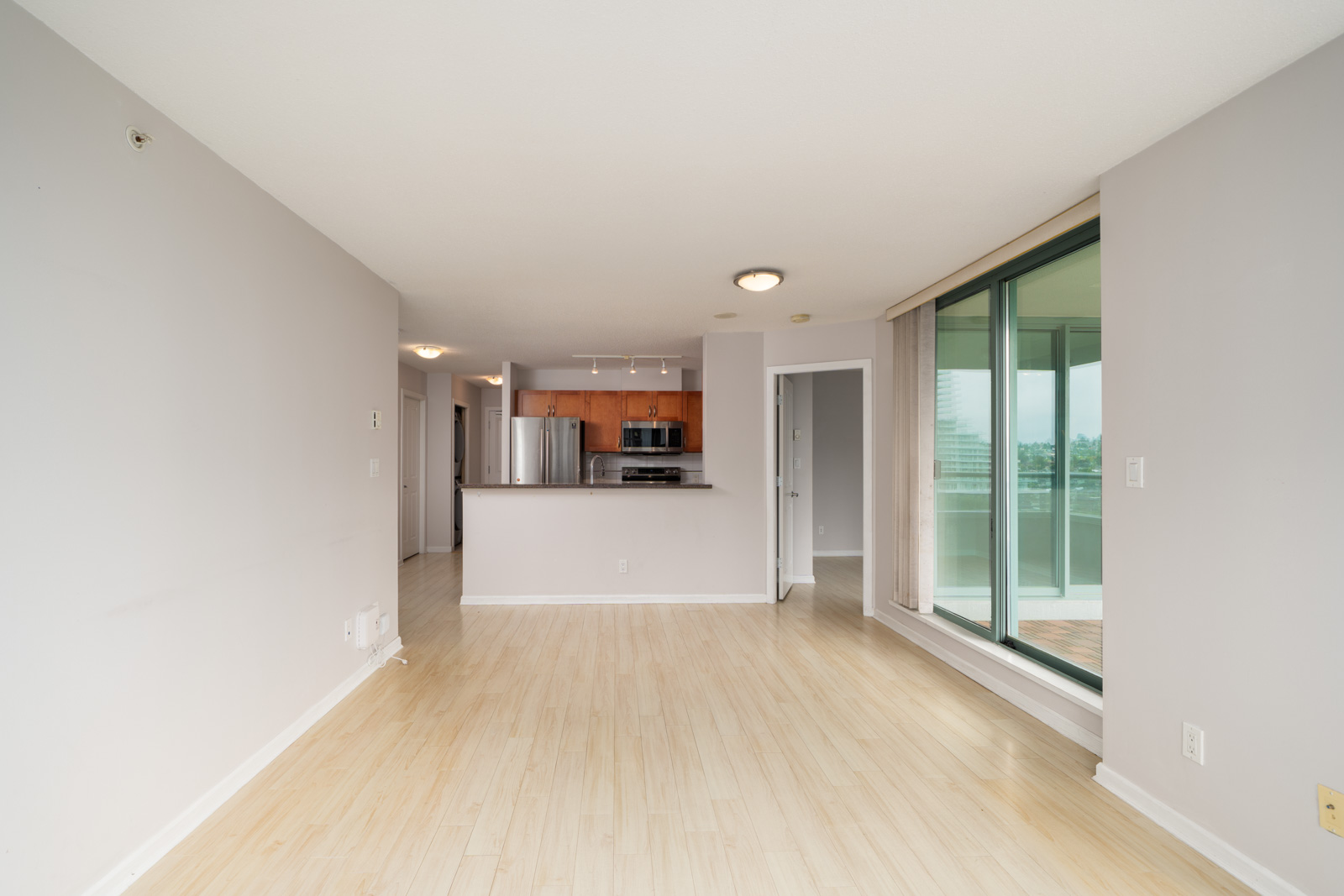 Unfurnished Burnaby condo on Halifax St with light wood floors, open kitchen, stainless appliances, and balcony access.