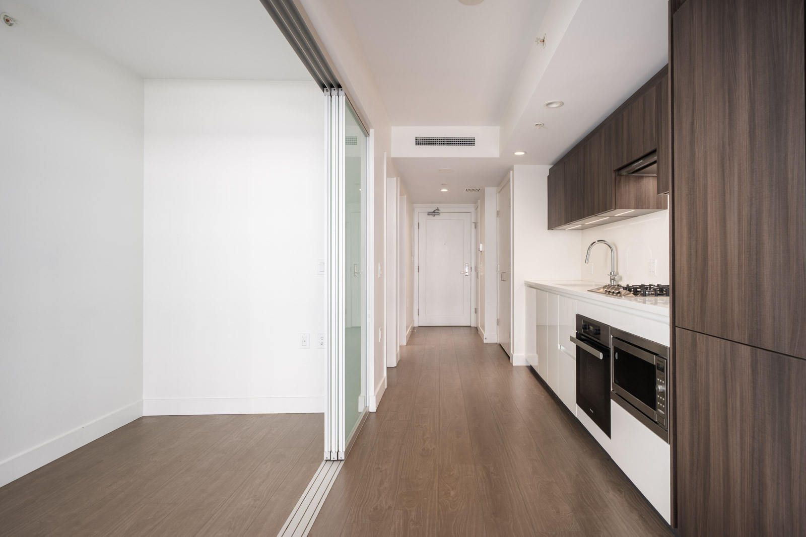 Richmond apartment with wood floors, white walls, built-in kitchen appliances, and sliding glass door dividing a small room.